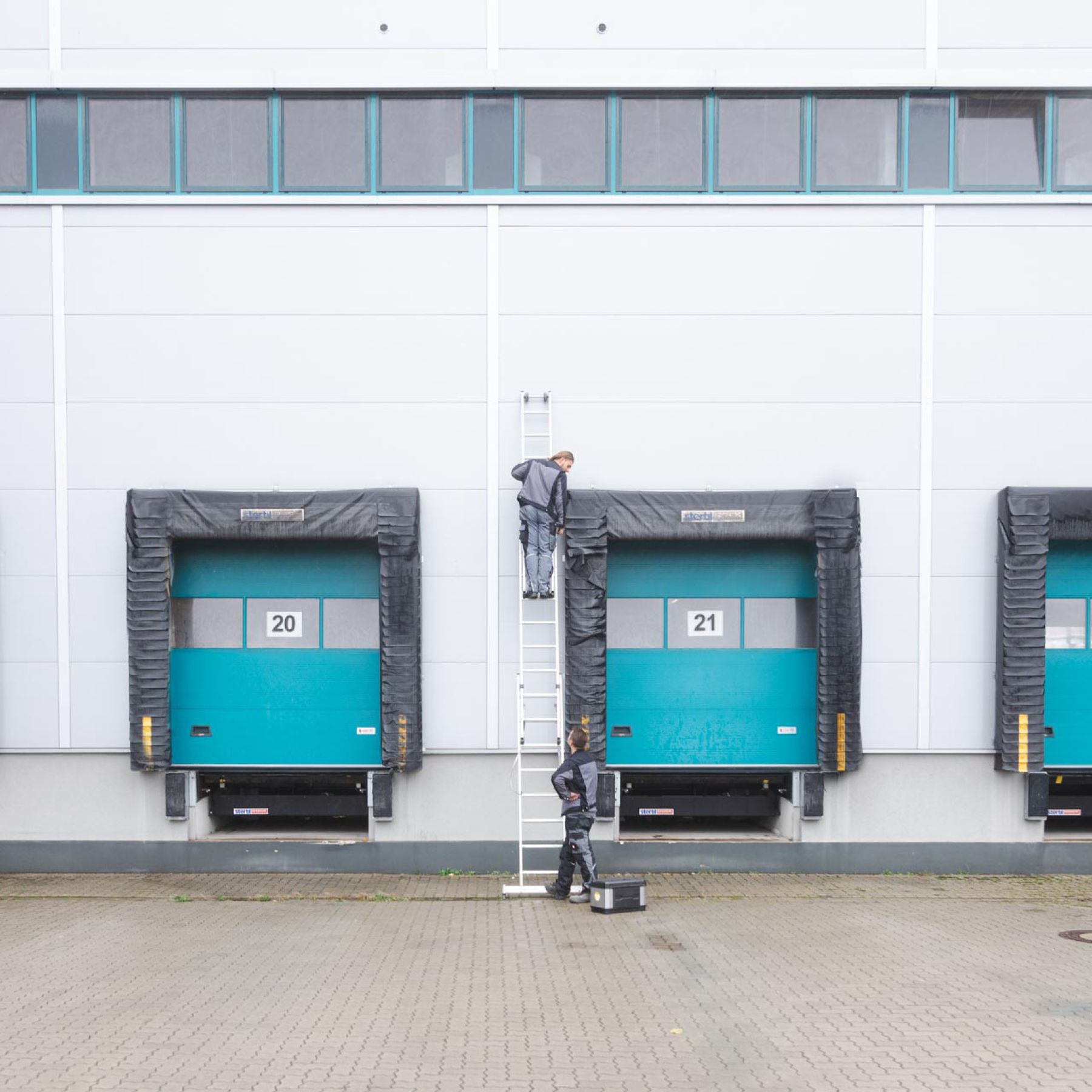 Zwei Mitarbeiter die sich um die Dichtungen von Industriehallentoren kümmern.