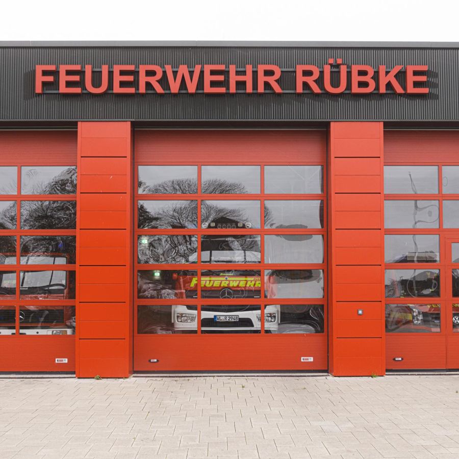 Feuerwehrwache mit einem Sektionaltor und dahinter steht ein Feuerwehrauto.